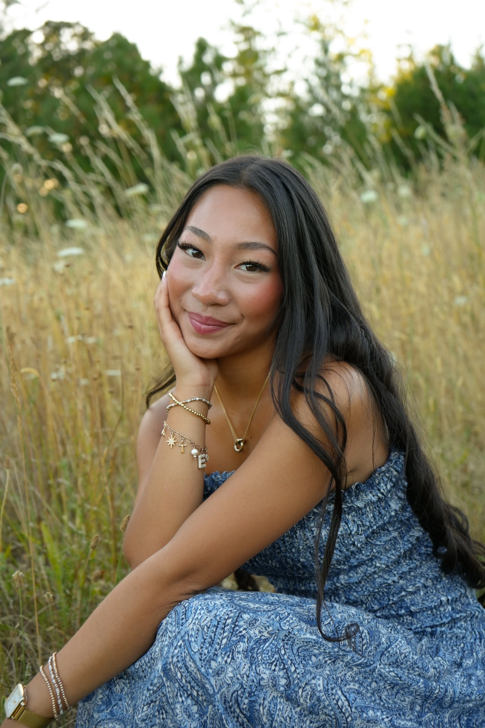 Woman in a blue patterned dress seated in a golden field