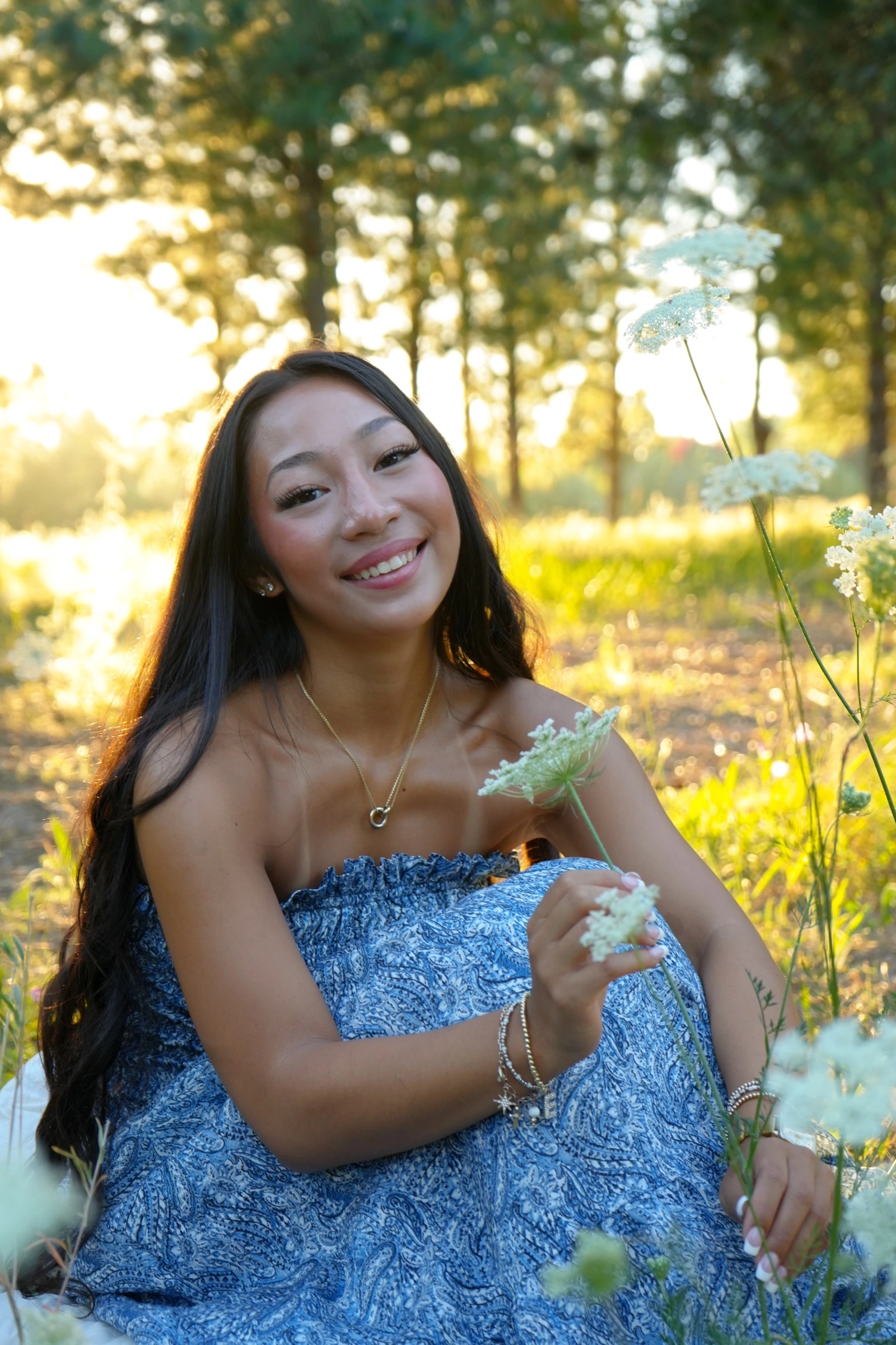 Woman in a blue patterned dress holding wildflowers in a golden meadow