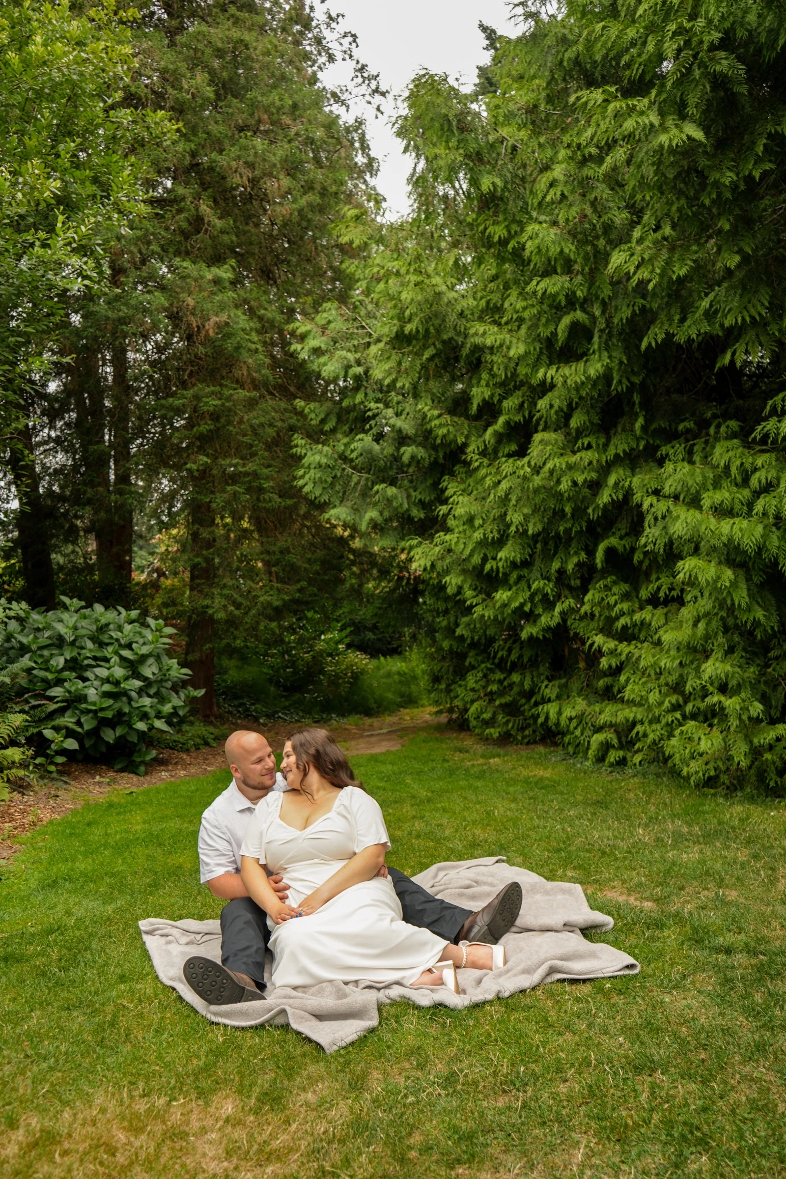 Couple sitting together on a picnic blanket in a green forest clearing