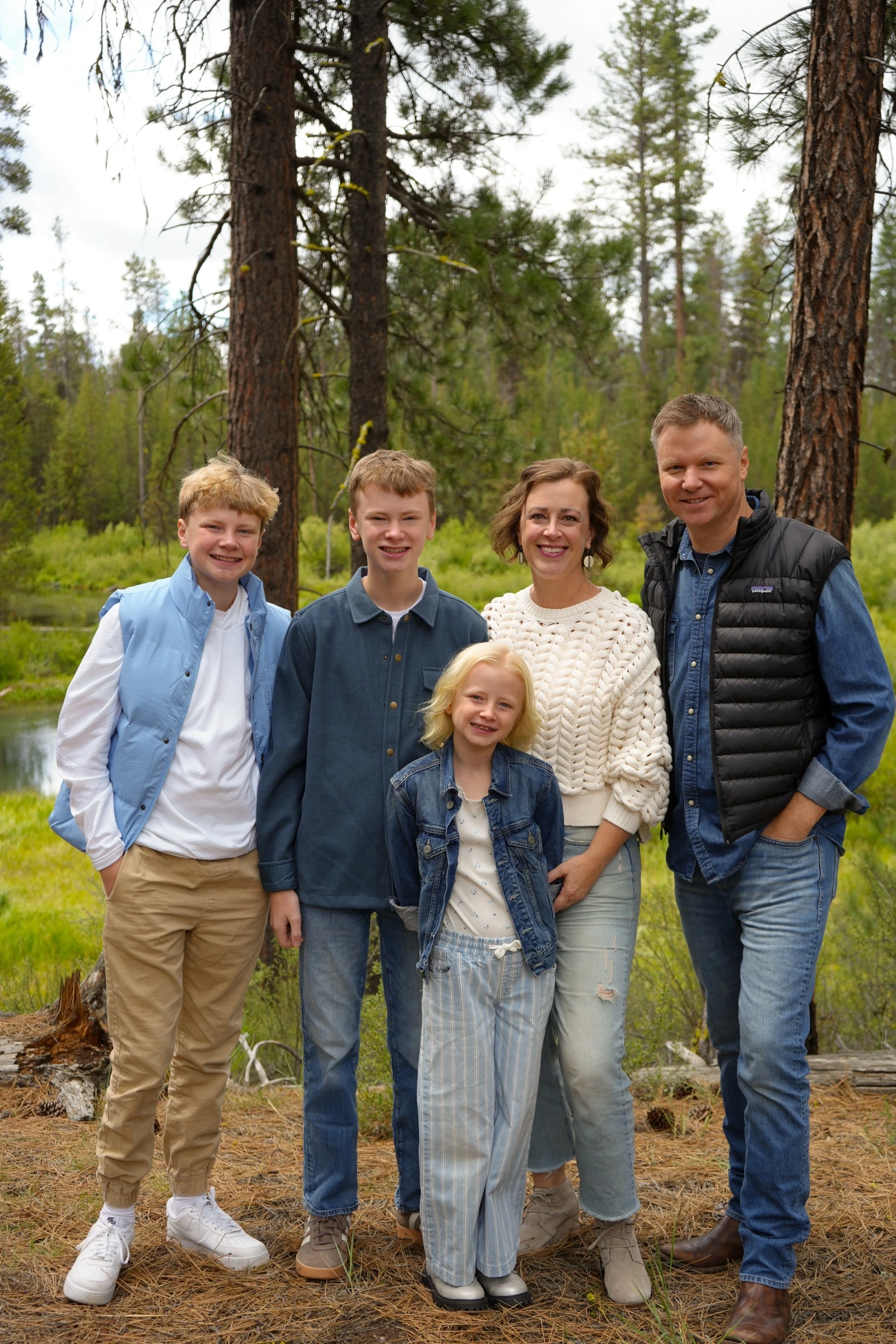 Family of five posing together in a forest clearing