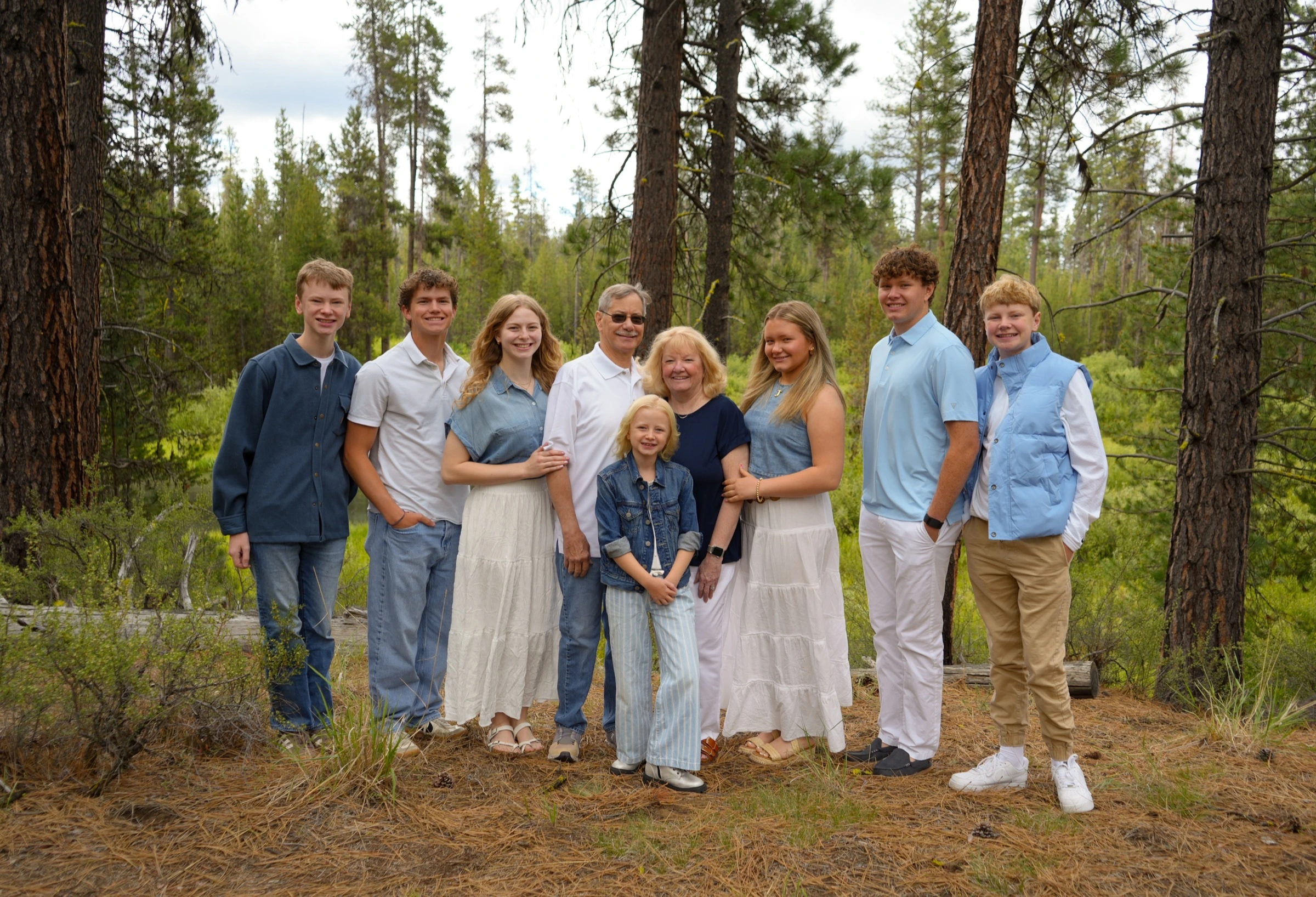 Multi-generational family posed among tall pine trees