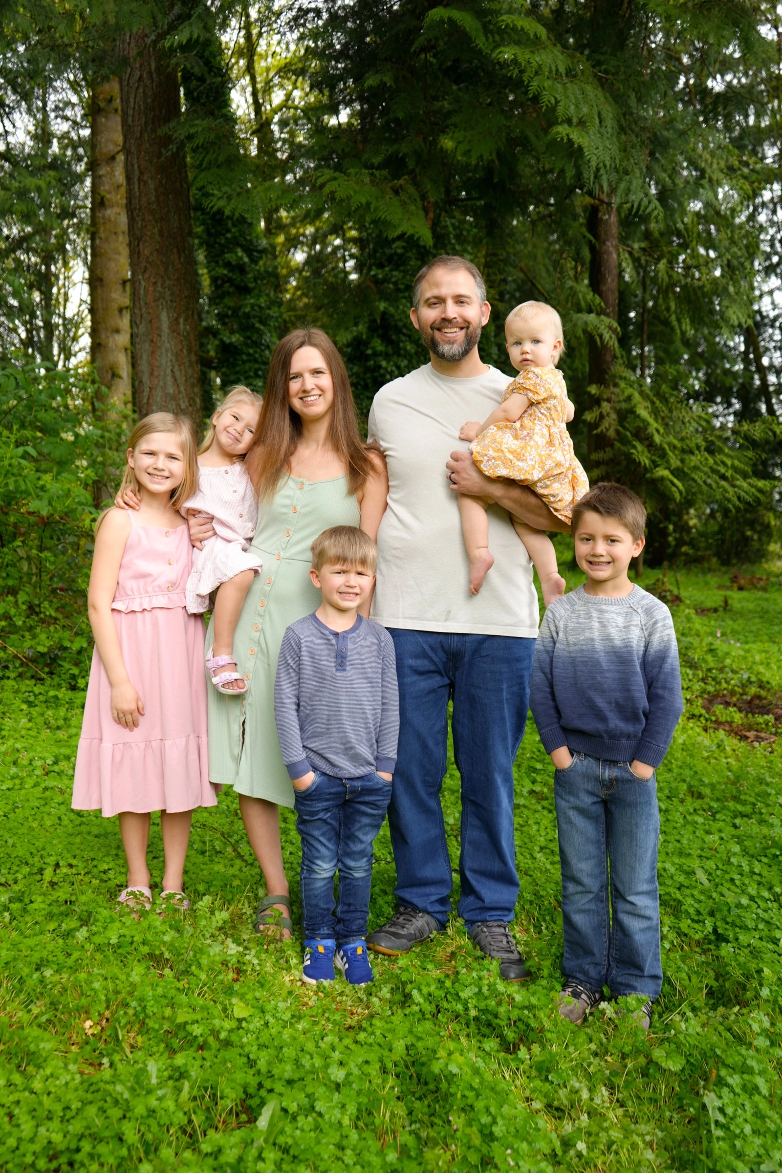 Family of seven smiling in a lush woodland setting