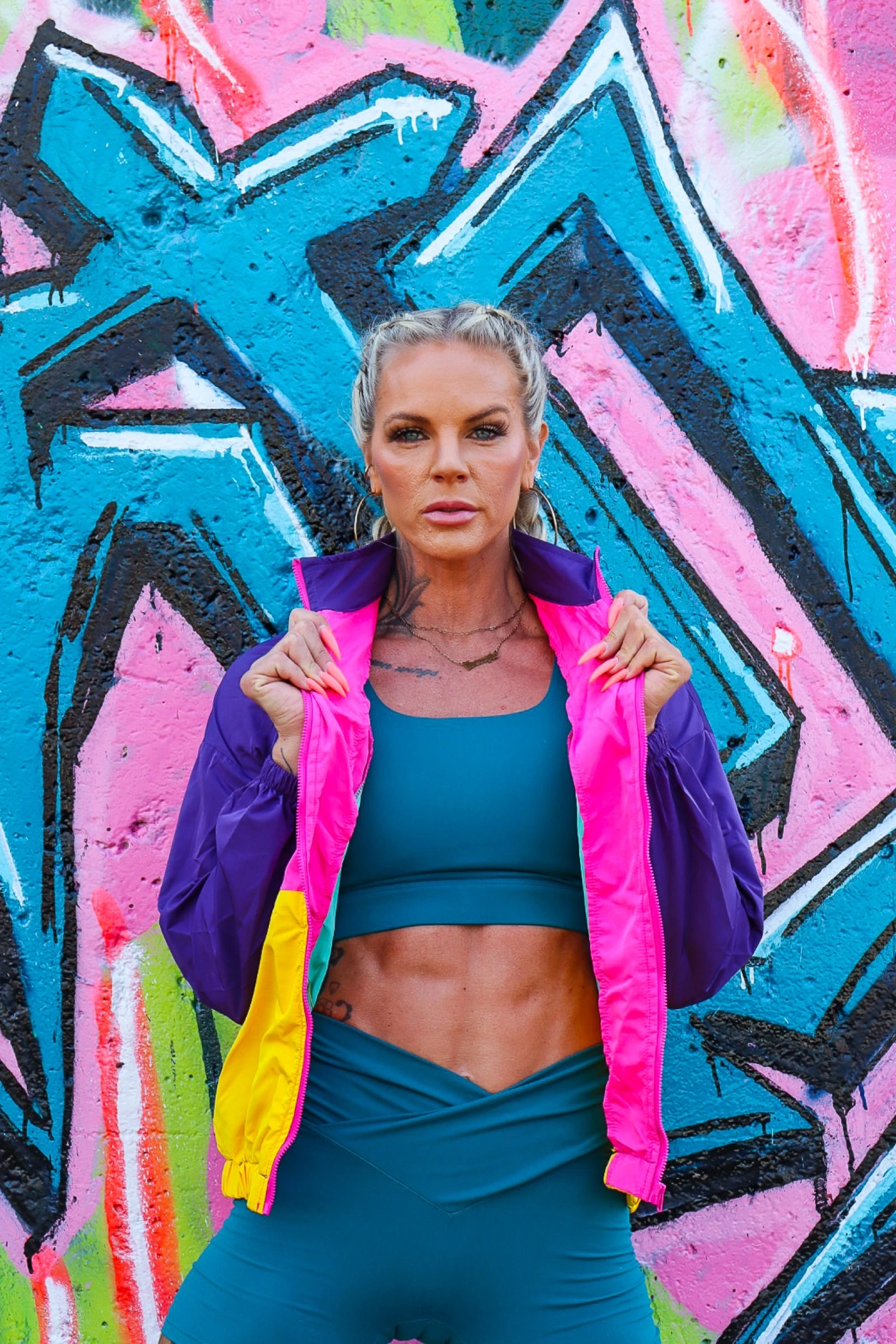 Athletic woman in colorful sportswear posing against a graffiti wall