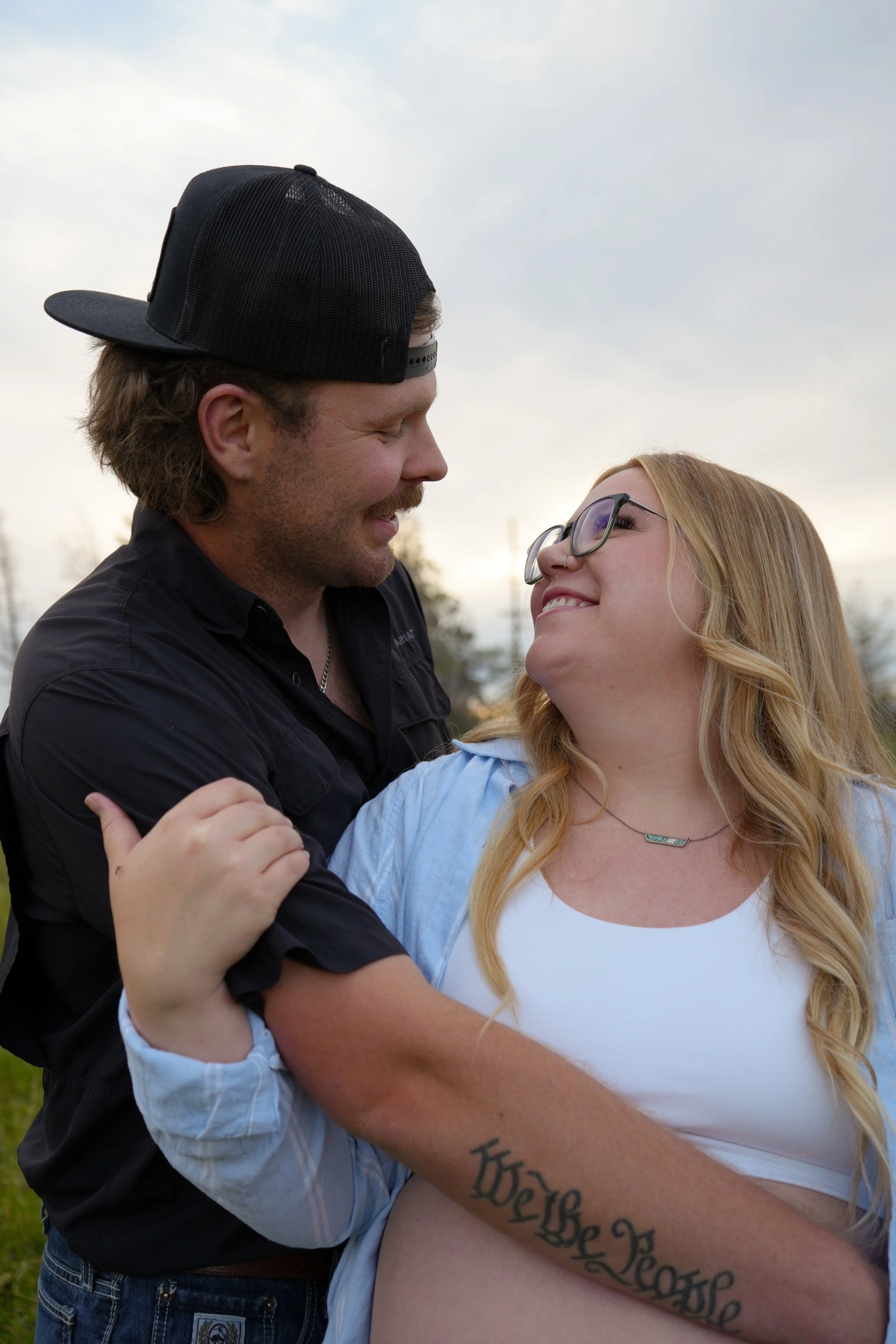 Close portrait of a pregnant couple smiling at each other outdoors
