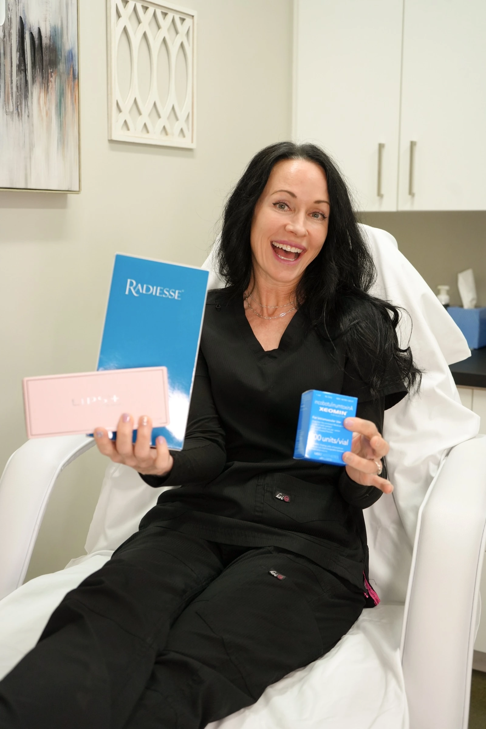 Medspa team member smiling while holding Radiesse and aesthetic product boxes