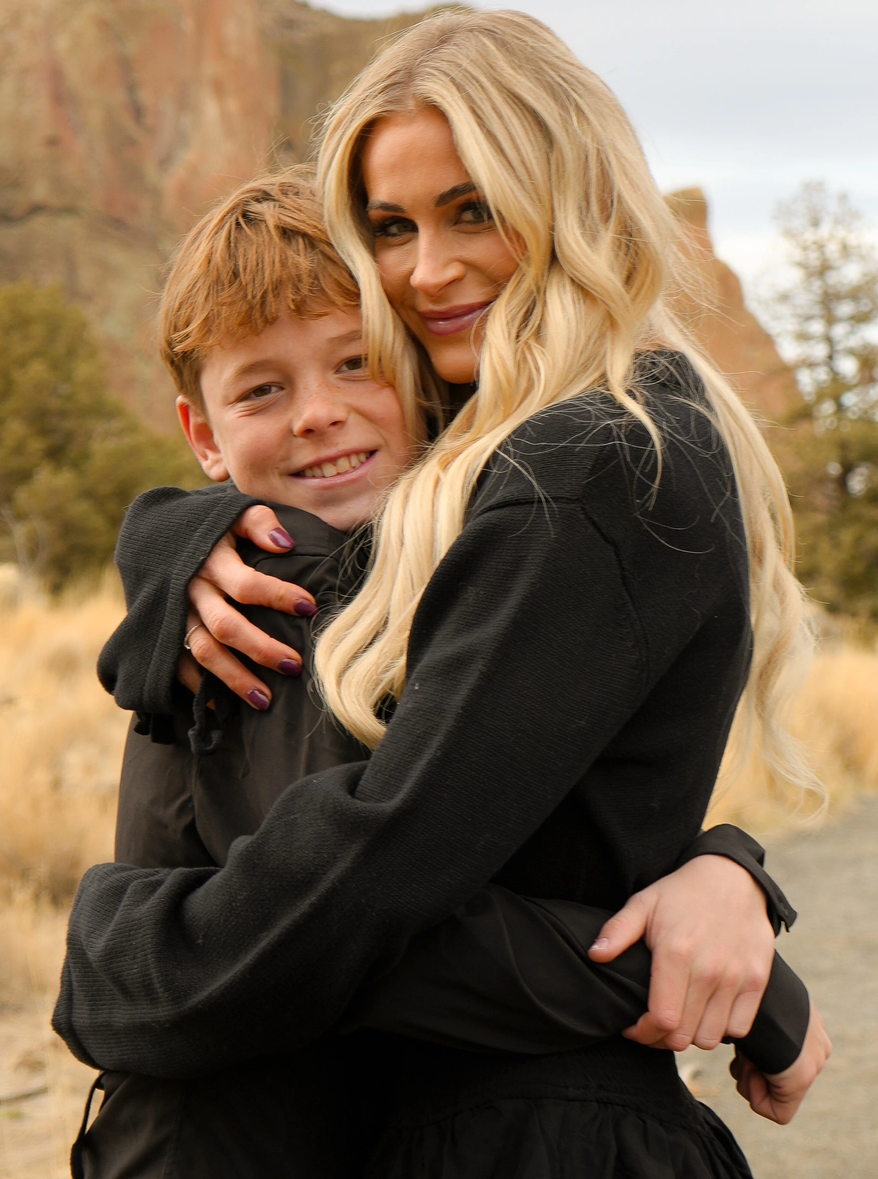 Mother and son embracing outdoors against desert rock formations