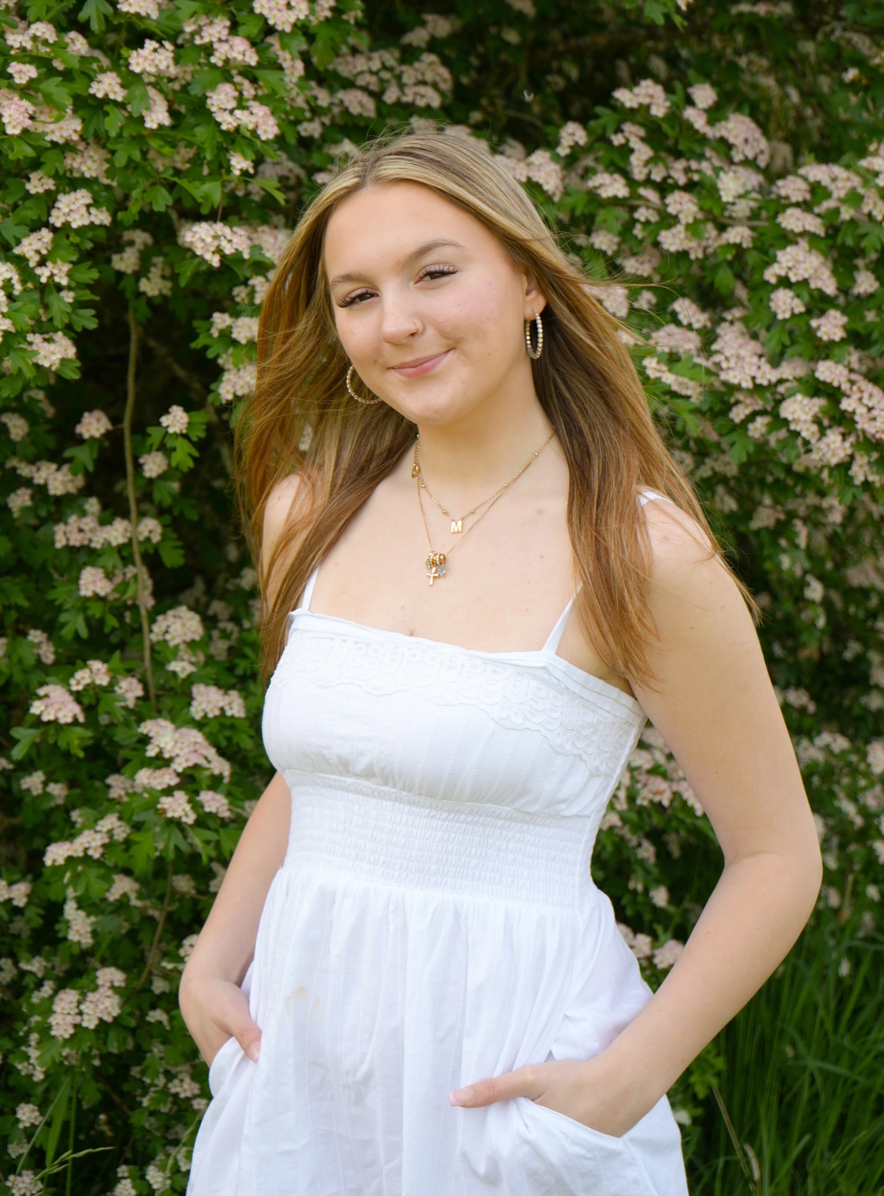 Woman in a white sundress standing in front of white blossoming bushes