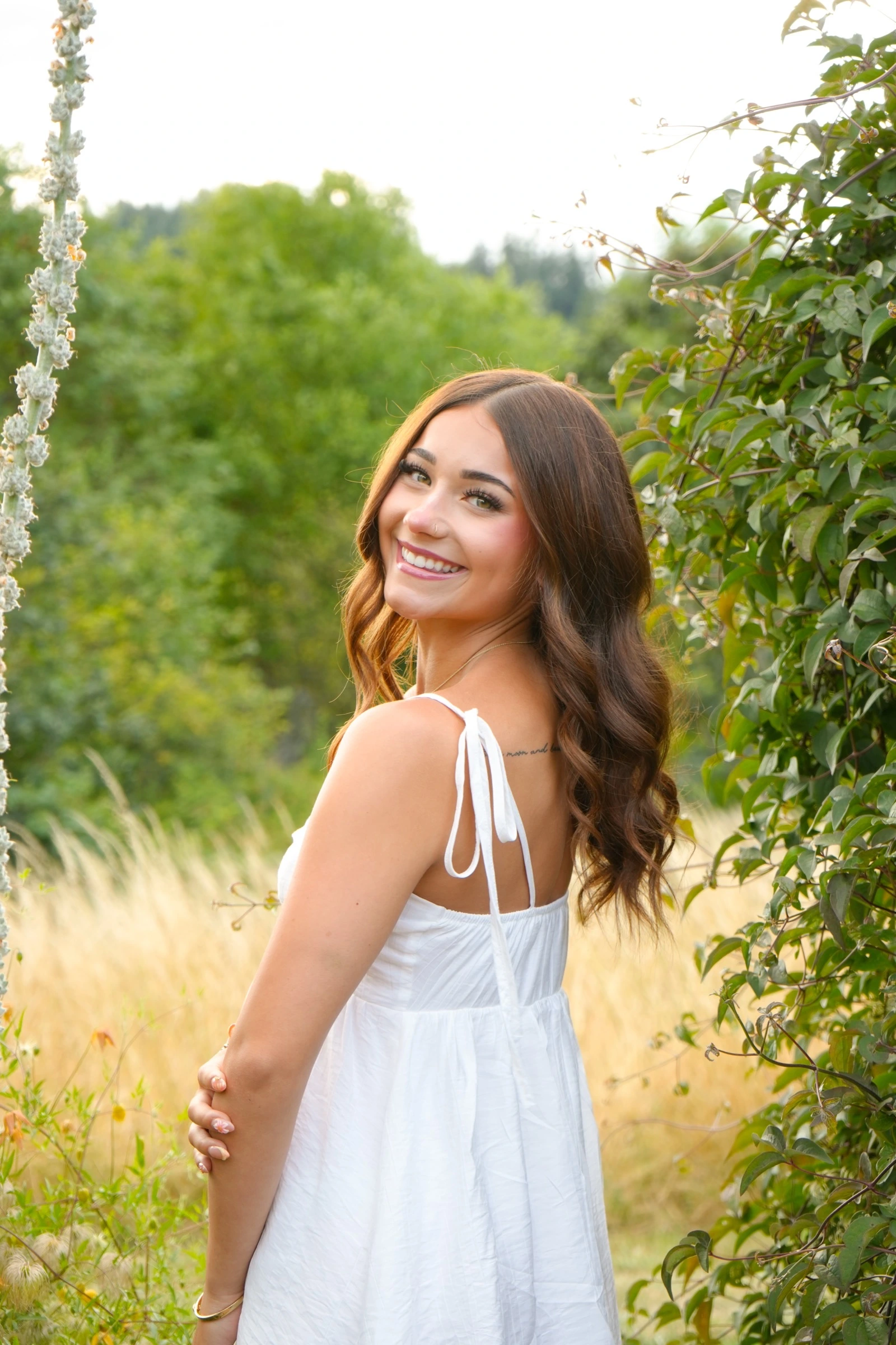 Woman in a white sundress looking over her shoulder in a sunlit meadow